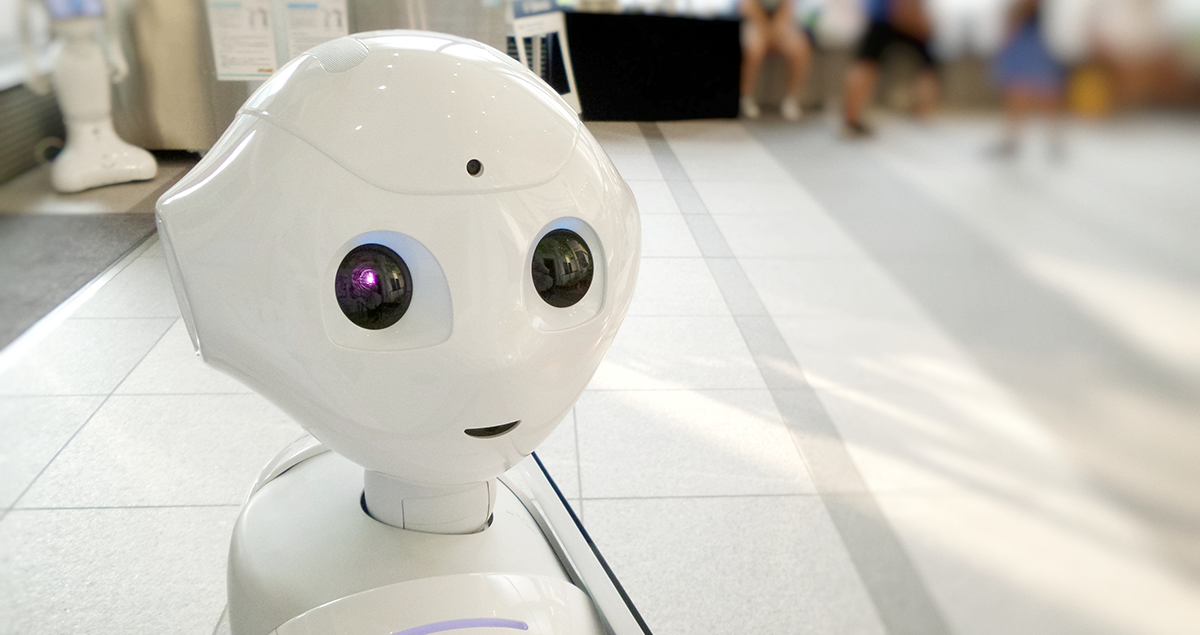 A photo of a humanoid robot in a shopping mall staring at the camera and smiling