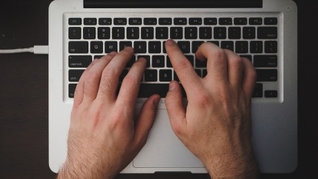 close up of hands typing on a laptop keyboard 